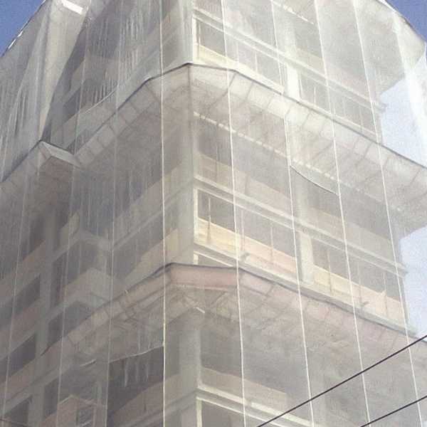 tela fachadeira branca instalada para proteção da fachada e andaimes de uma obra