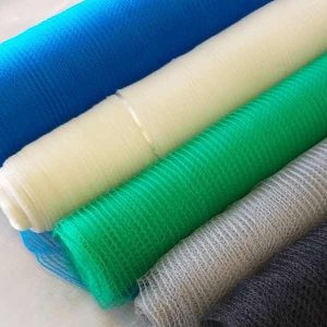 Rolos de tela antigranizo colorida alinhados em azul, branco, verde, cinza e preto, em close sobre superfície clara.