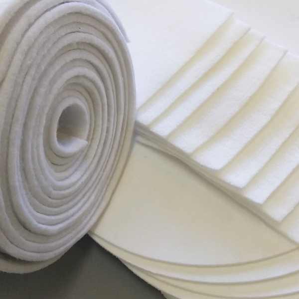 Rolo de feltro branco com tiras e discos recortados, materiais utilizados para confeccionar bags e elementos filtrantes sob medida para tratamento de água em tanques de piscicultura e larvicultura.