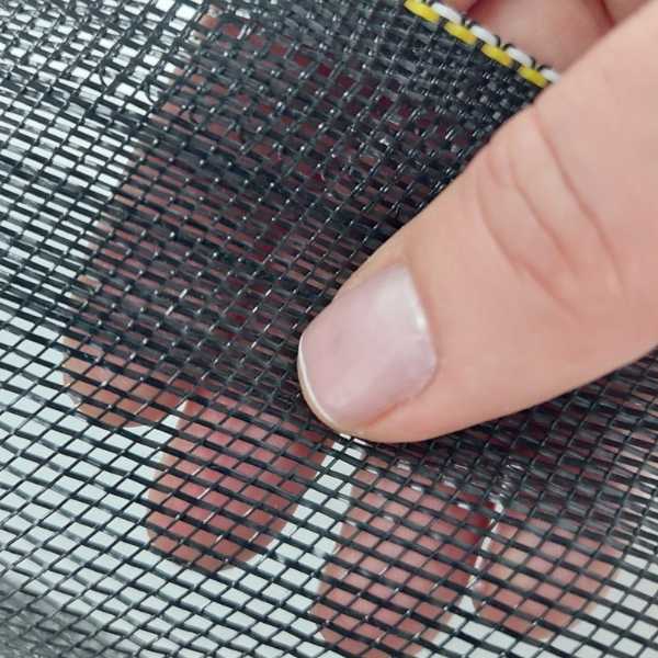 Mão segurando uma tela de sombreamento preta de malha fina, mostrando os detalhes do entrelaçamento dos fios